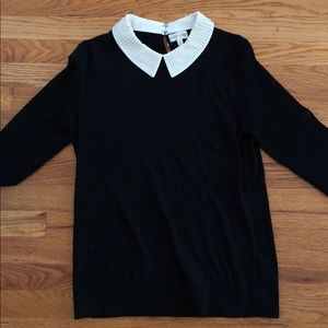 Black sweater with pearl detail at collar.